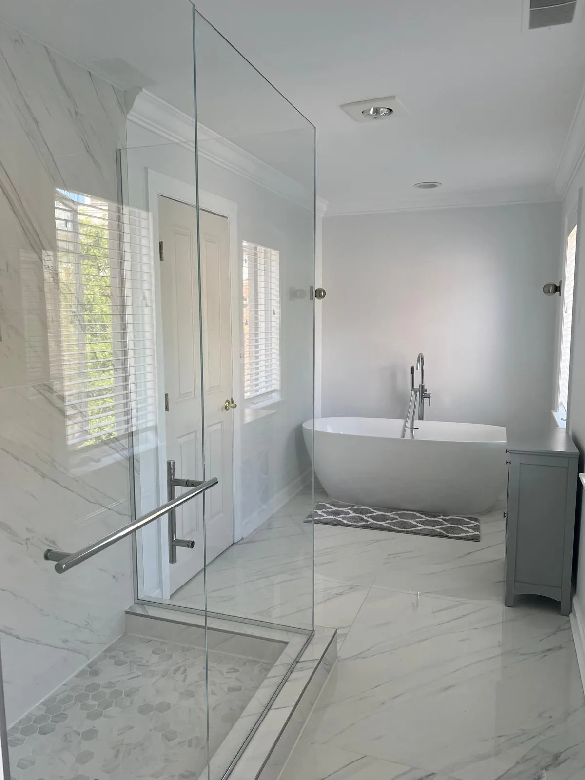 Marble-tiled bathroom with a freestanding tub and glass shower