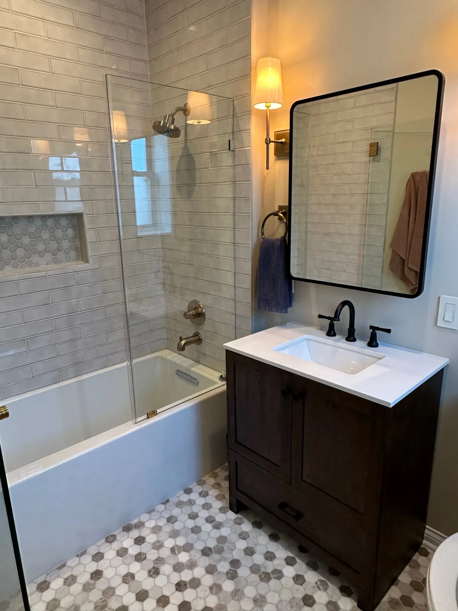 Dark wood bathroom vanity with mirror and wall sconces