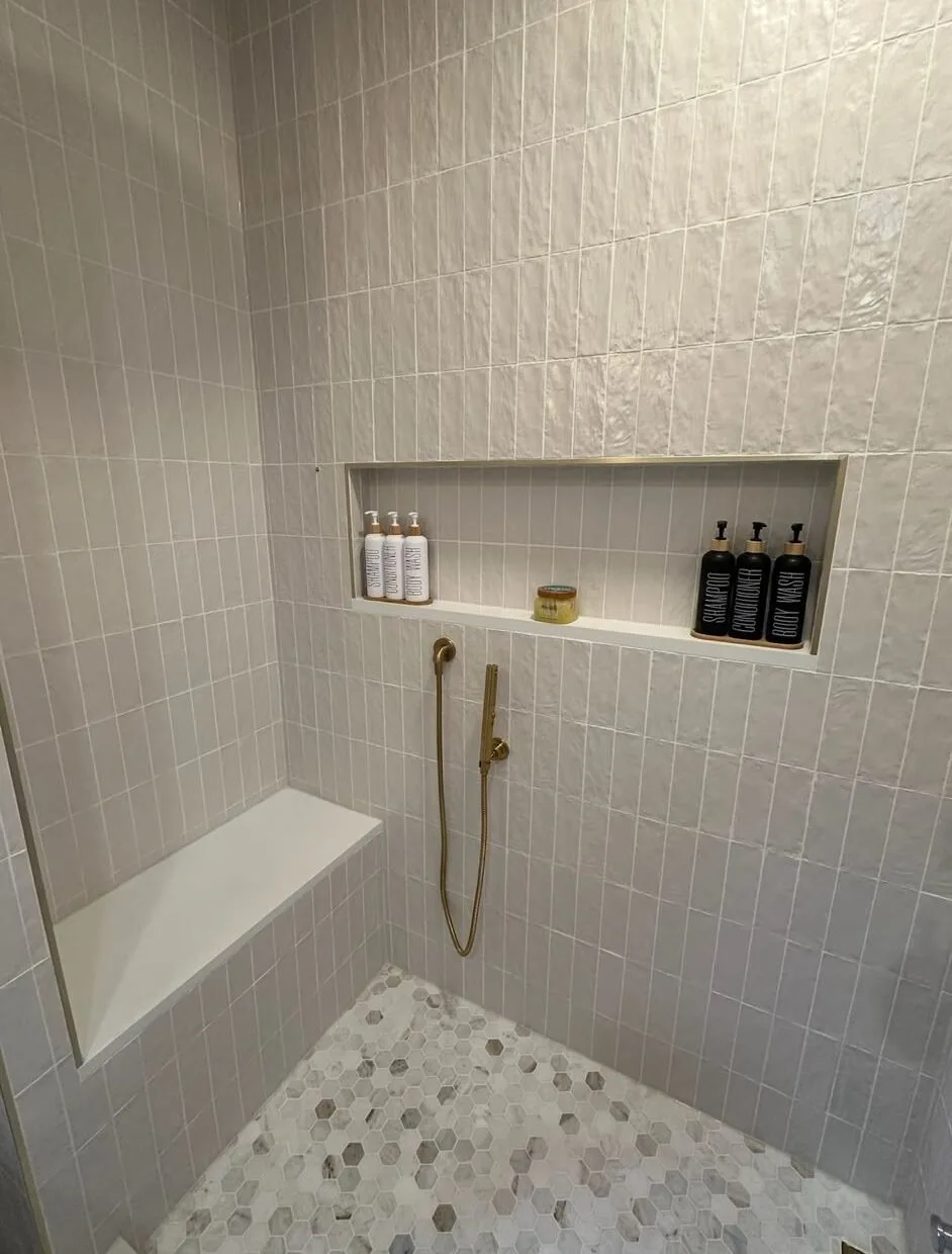 White tiled shower with a built-in bench and recessed niche