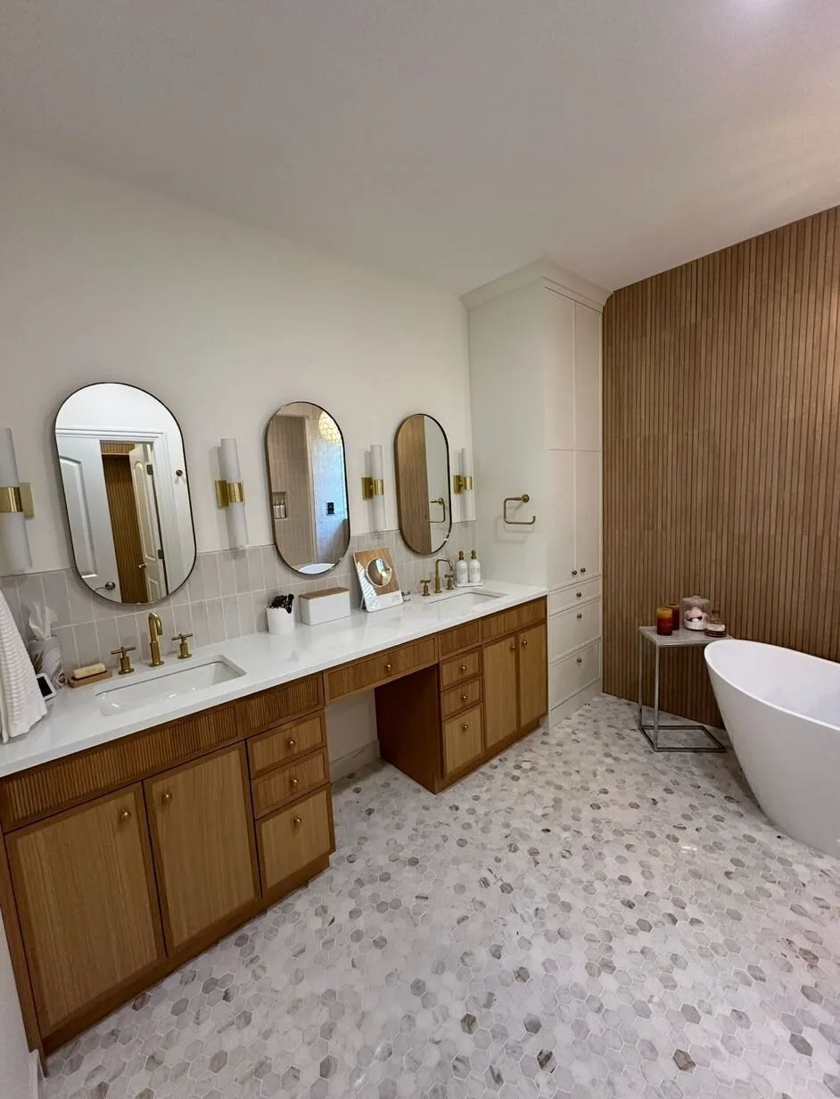 Wood double vanity with oval mirrors and a freestanding tub