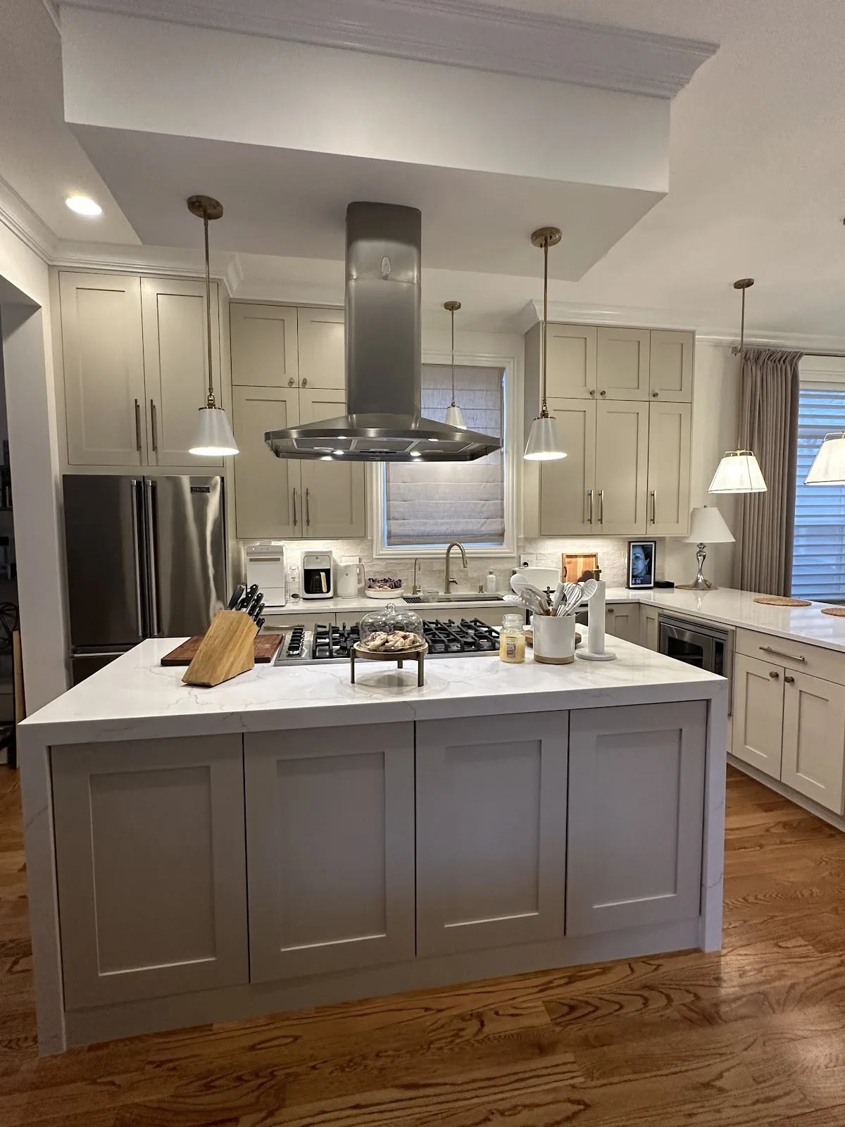 Greige shaker kitchen with a quartz island and stainless hood