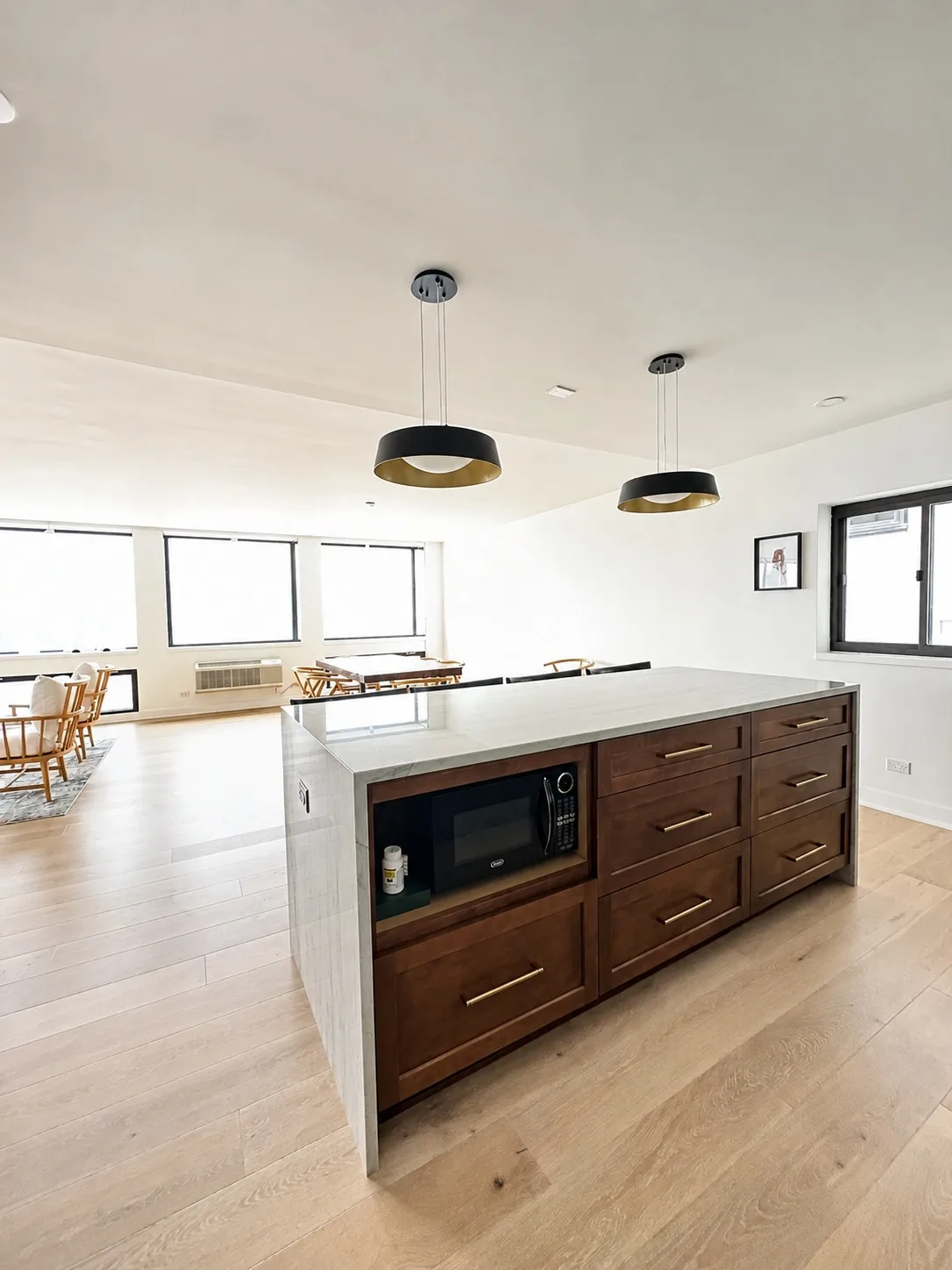 White kitchen with a dark wood island and black pendants