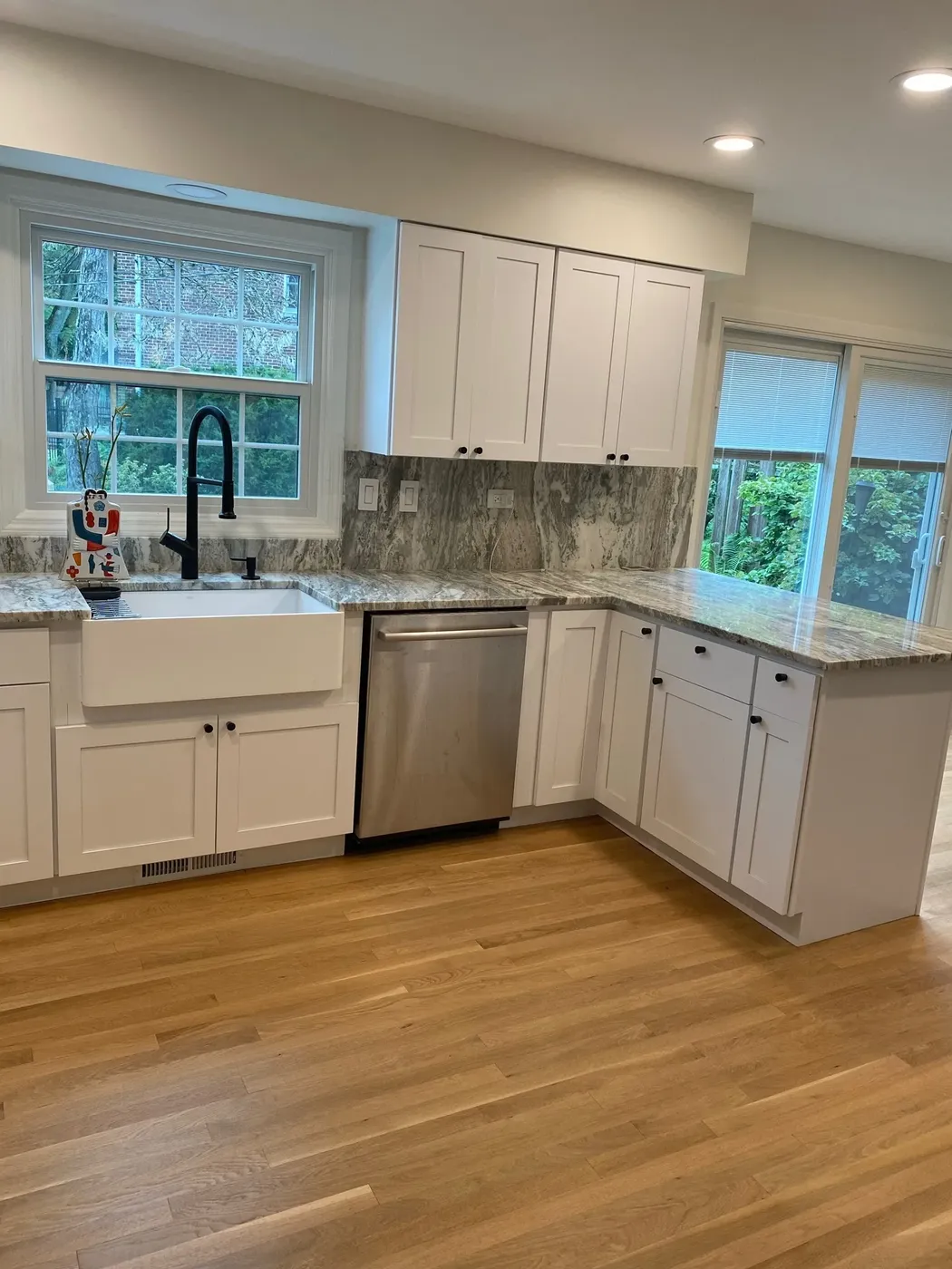 Wide white shaker kitchen with stone counters and oak flooring